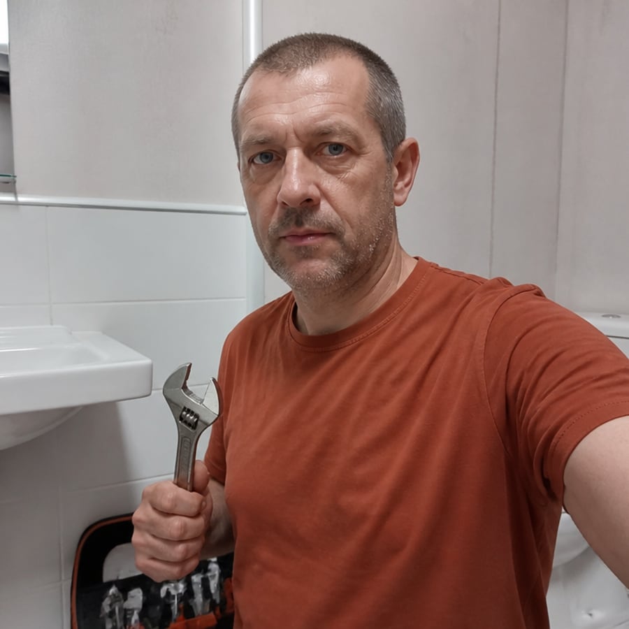 Сантехник ремонтирует смеситель под раковиной